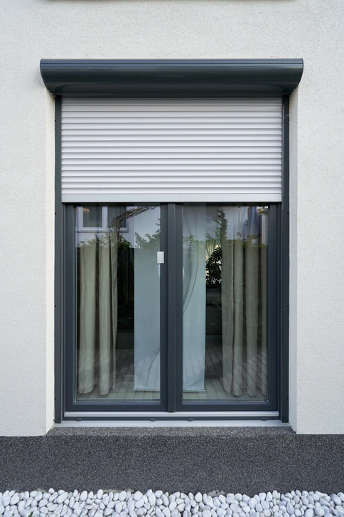 Façade extérieure d'un bâtiment moderne avec porte-fenêtre à deux vantaux et volet roulant électrique