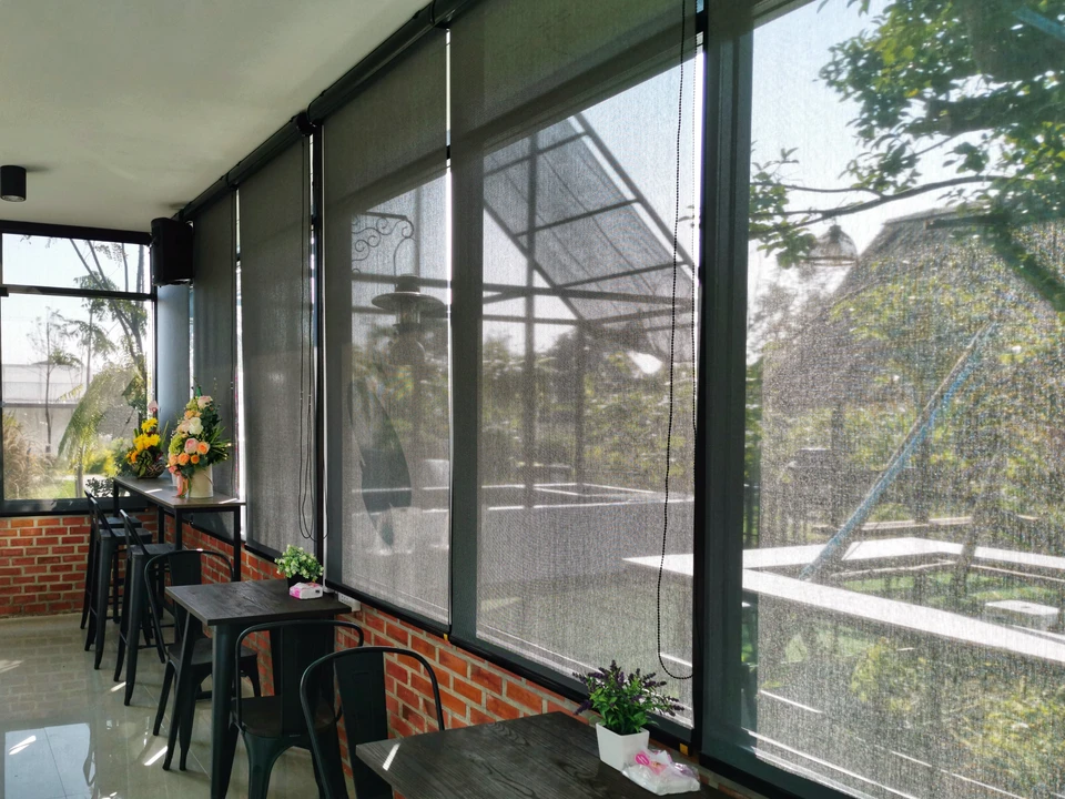 Terrasse couverte avec stores enrouleurs gris filtrant la lumière naturelle