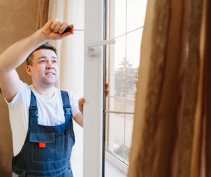 un réparateur répare, ajuste ou installe des fenêtres en métal-plastique dans l'appartement