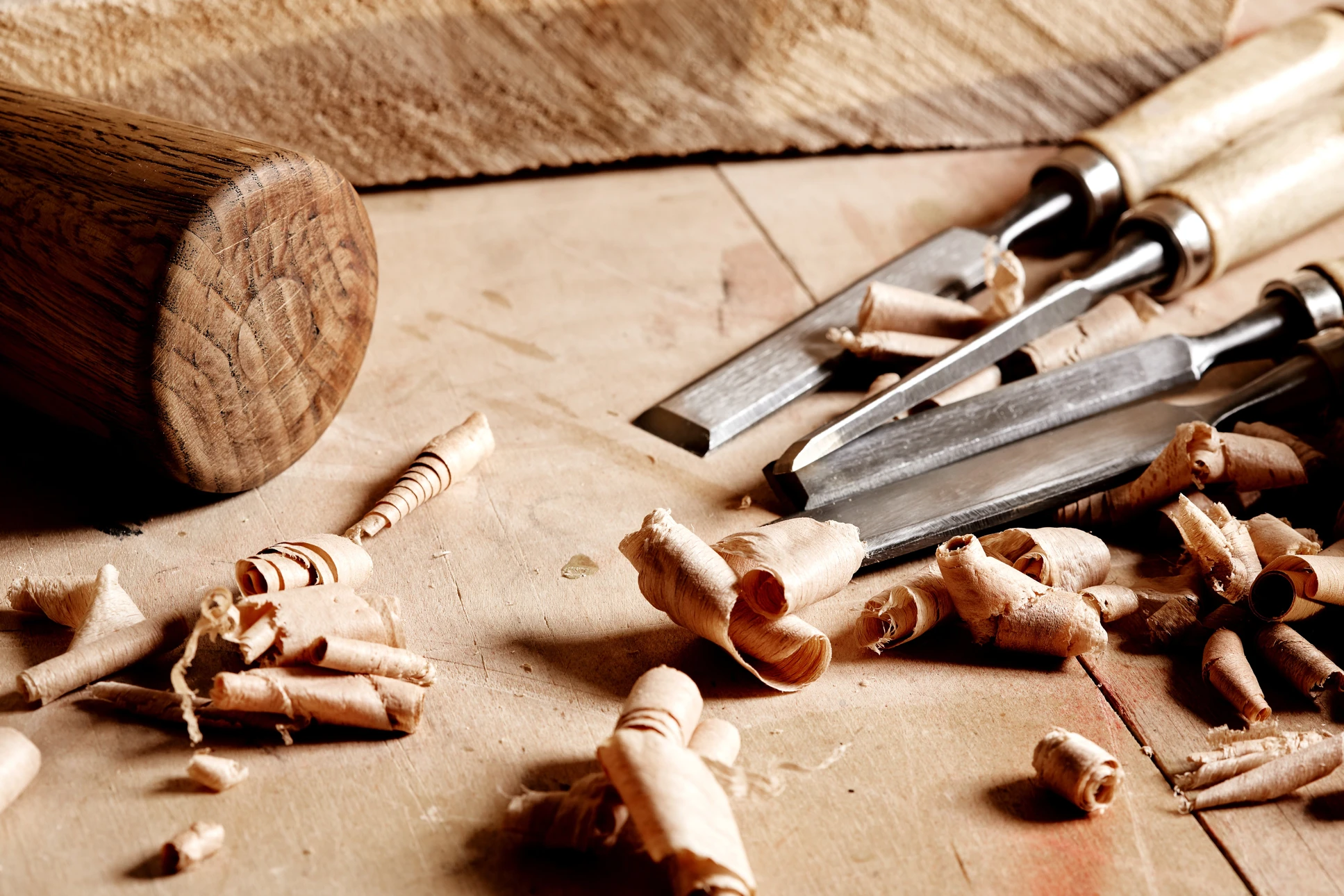 Artisan menuisier travaillant le bois dans son atelier, utilisant un rabot manuel sur une planche posée sur établi